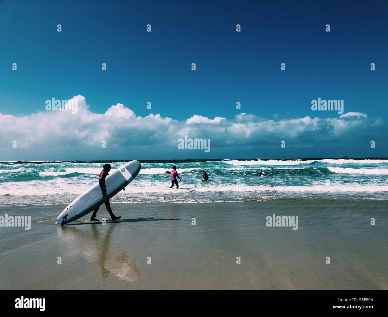 A surfer walking along the beach at Sennen cove in Cornwall - Smartphone Captured Stock Image