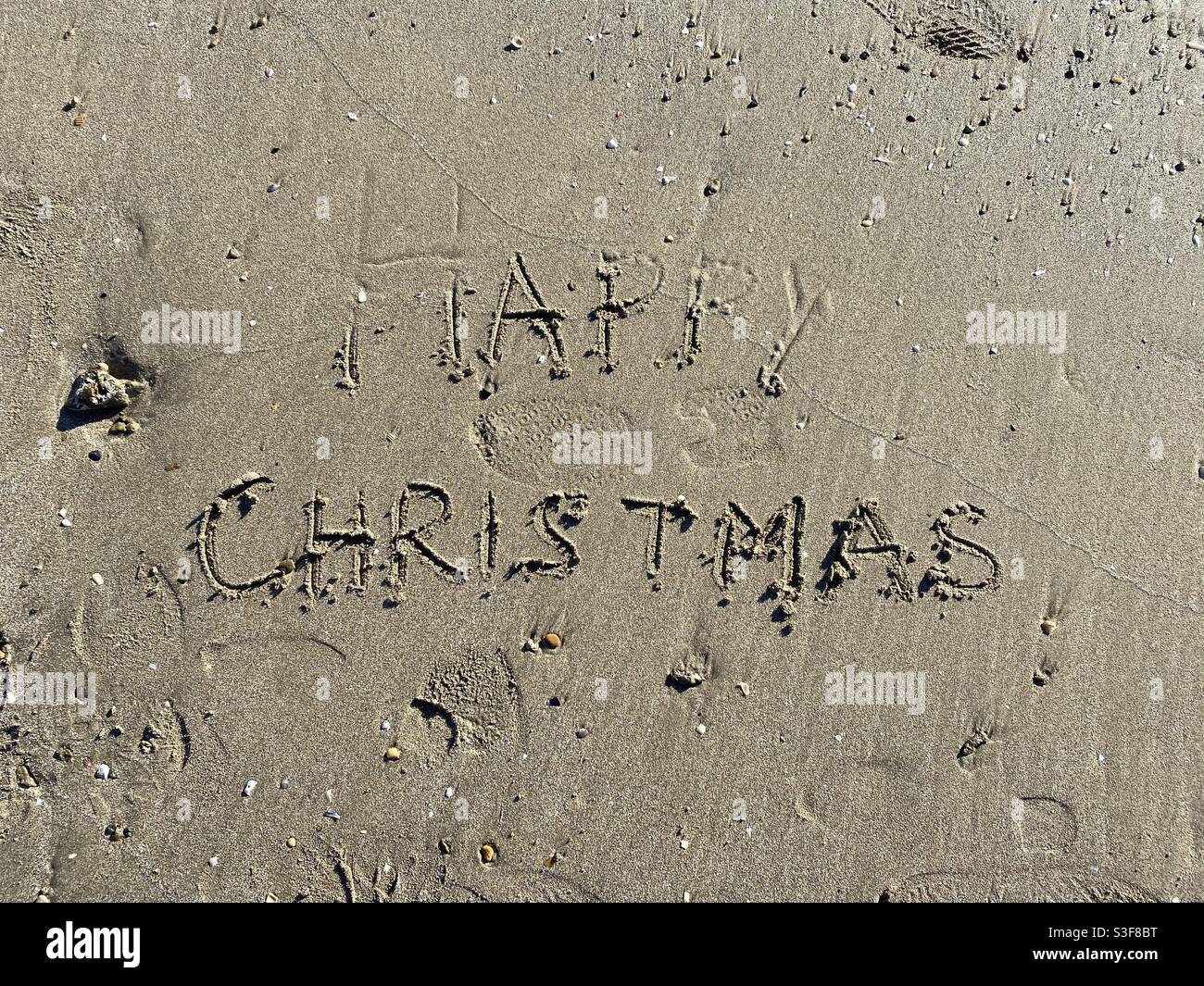 Happy Christmas written in the sand in Palavas les Flots near Carnon Plage and Montpellier, Occitanie, south of France - Smartphone Captured Stock Image