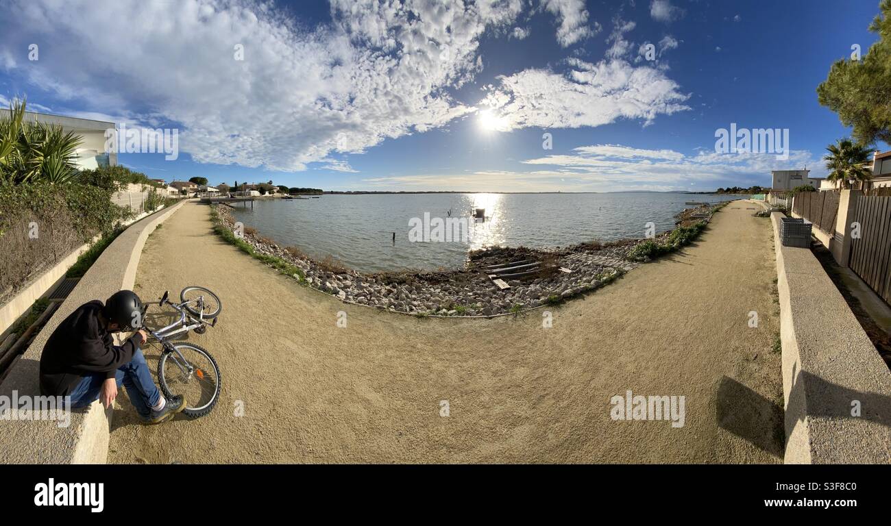 Wide panorama of a board walk on the waterfront of a salt lake in Mauguio near Palavas les Flots, Carnon Plage and Montpellier, Occitanie, south of France - Smartphone Captured Stock Image