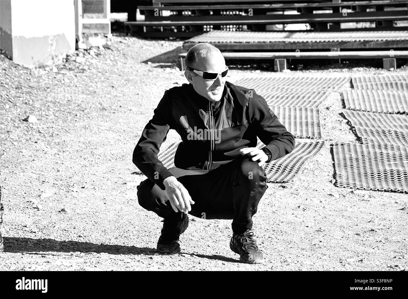 Smiling man squatting in sunglasses - Smartphone Captured Stock Image