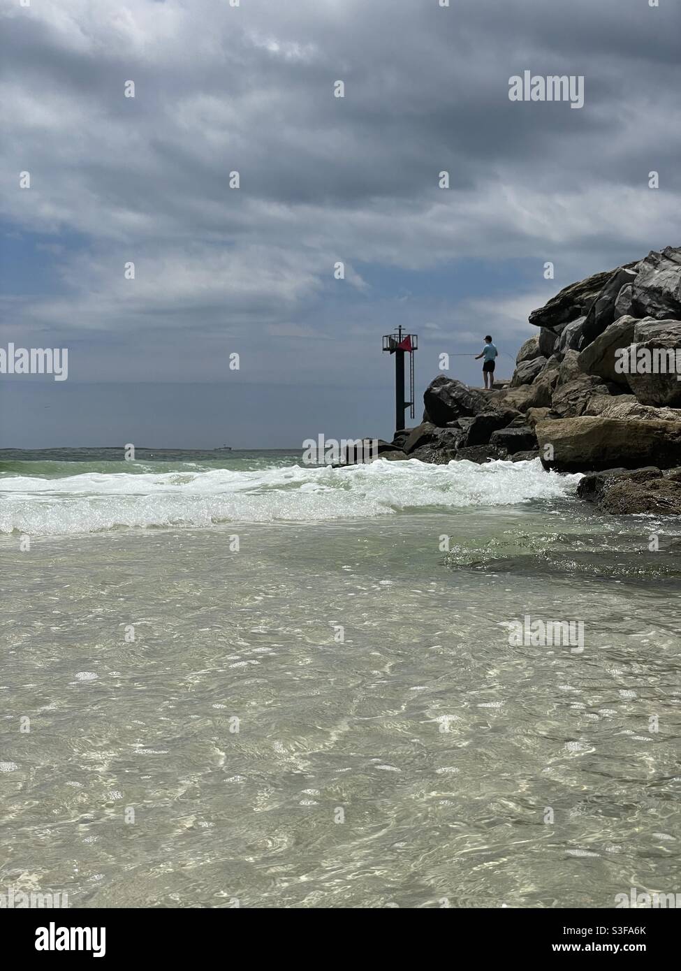 Man fishing on rocky jetties at East Pass Destin Florida Stock Photo