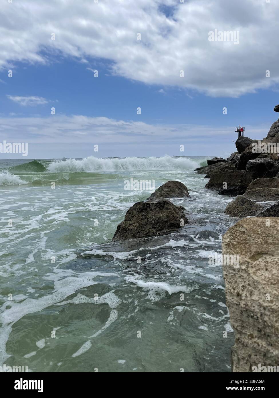 Ocean waves with rocky jetties at East Pass Destin Florida - Smartphone Captured Stock Image