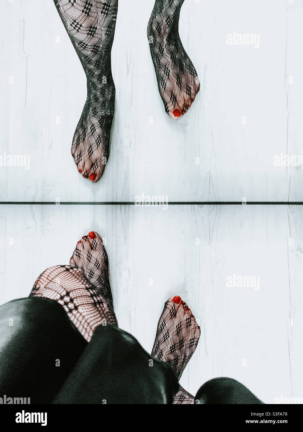 Woman wearing patterned tights reflecting in a mirror - Smartphone Captured Stock Image