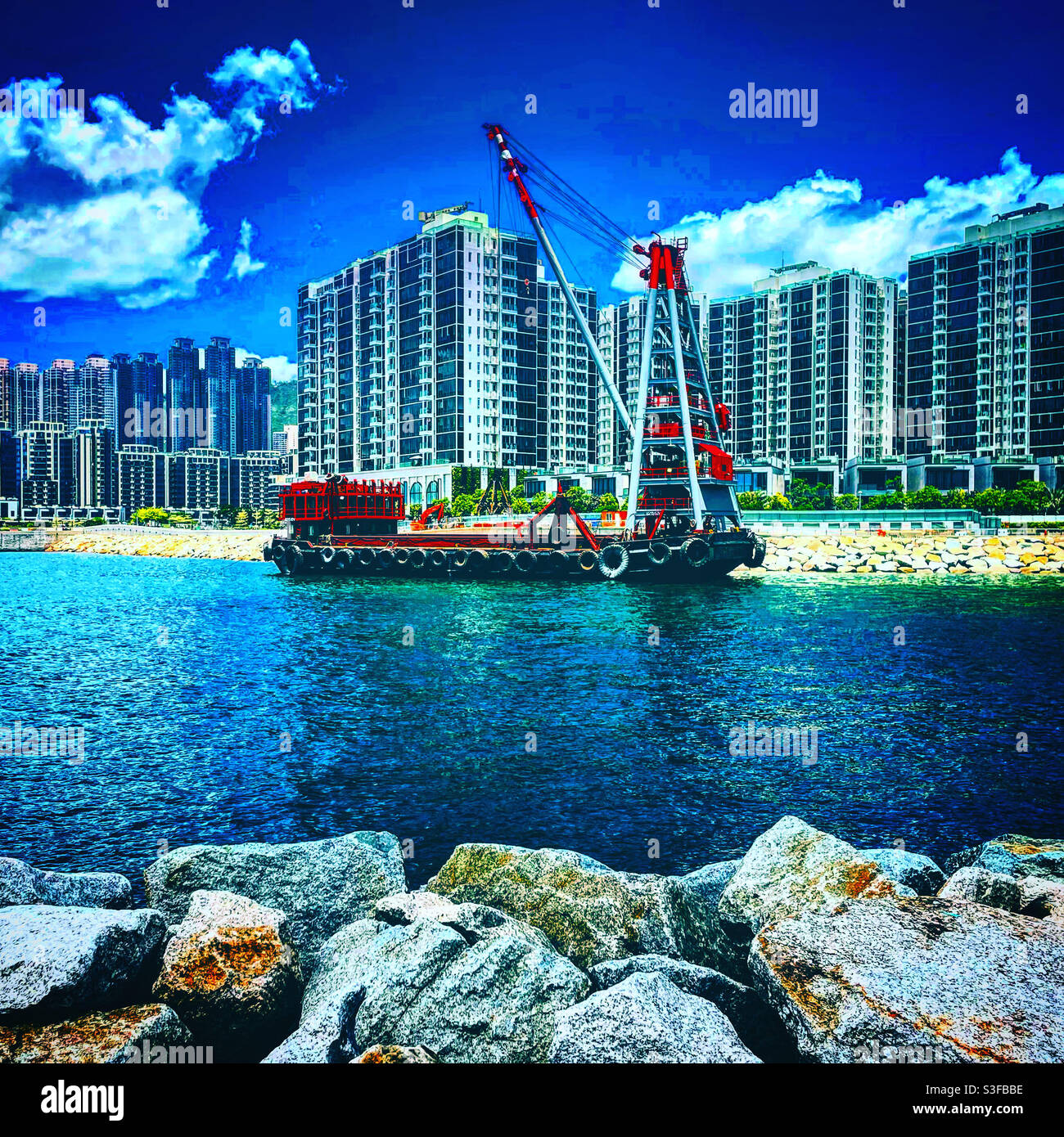 Crane on a boat near a construction dite in hong kong. We can see towers and condominiums Stock Photo