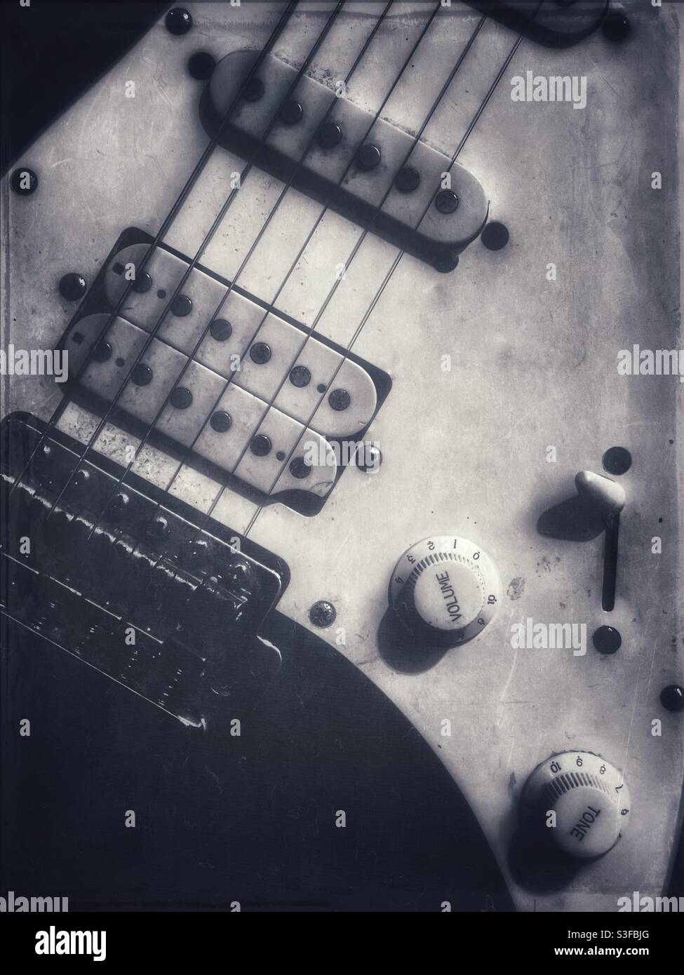 Beat up old electric guitar with faded grunge effects in black and white Stock Photo