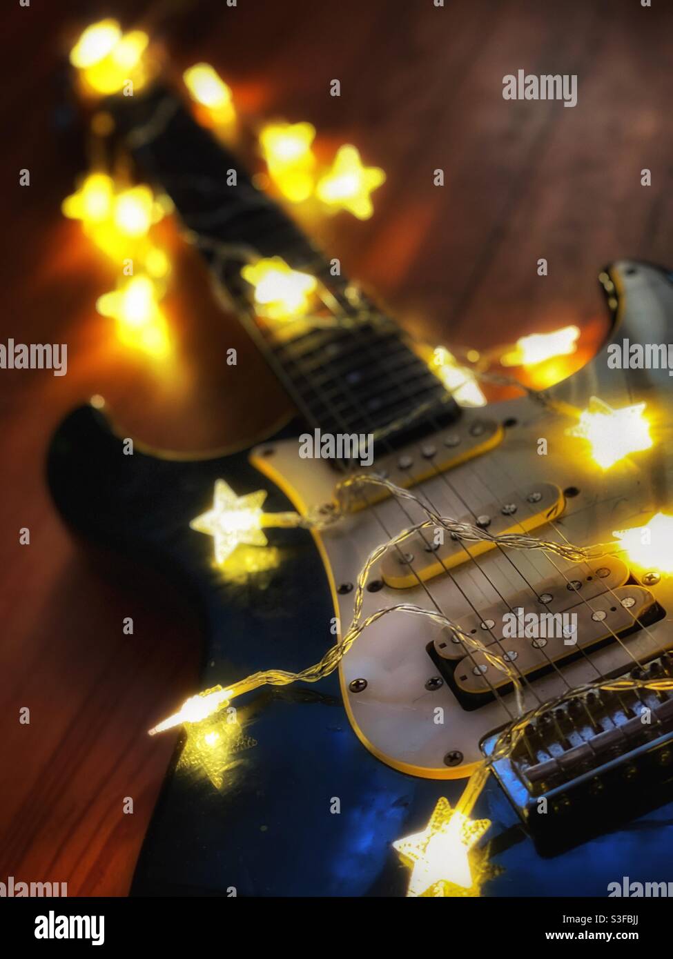 Old electric guitar draped with star shaped twinkle lights Stock Photo