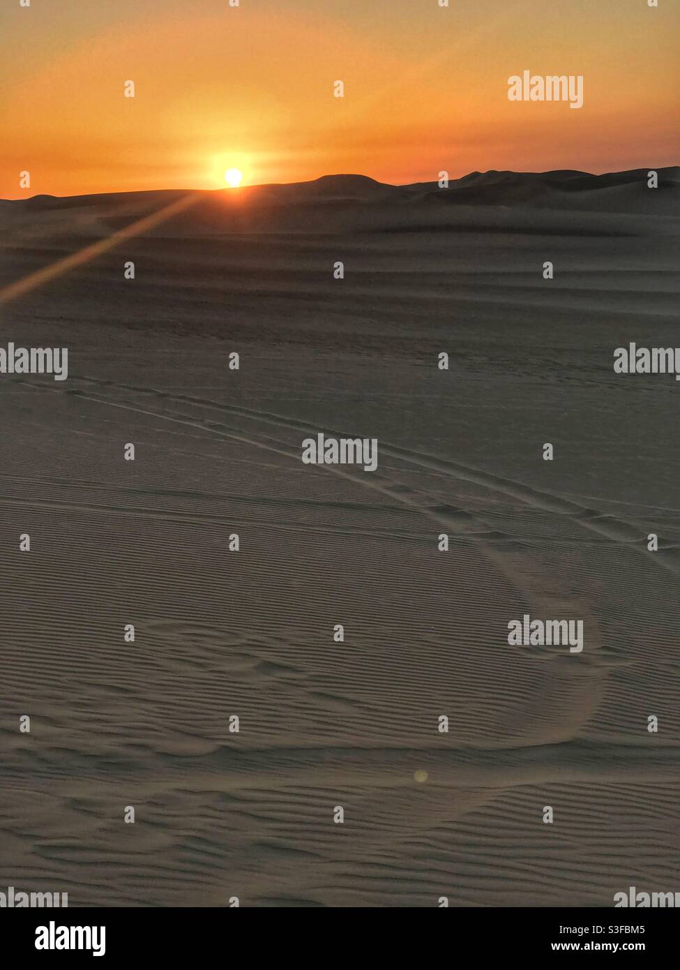 Sunset over dune buggy tracks in the sand in Huacachina, Peru - Smartphone Captured Stock Image