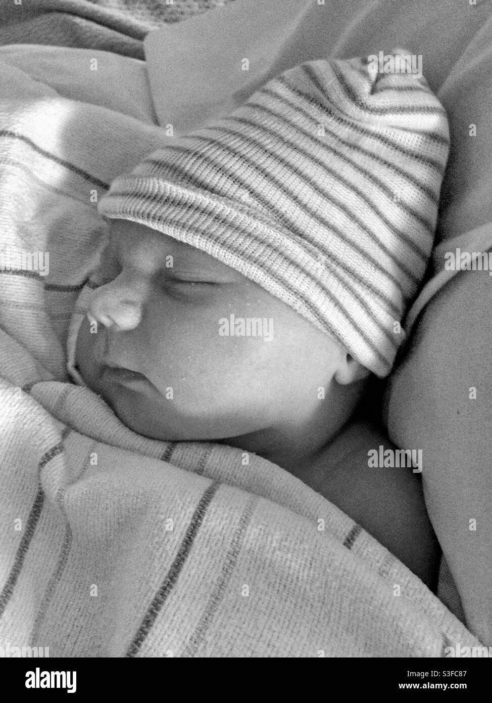 Newborn baby sleeping, with hat and blanket, in black and white - Smartphone Captured Stock Image