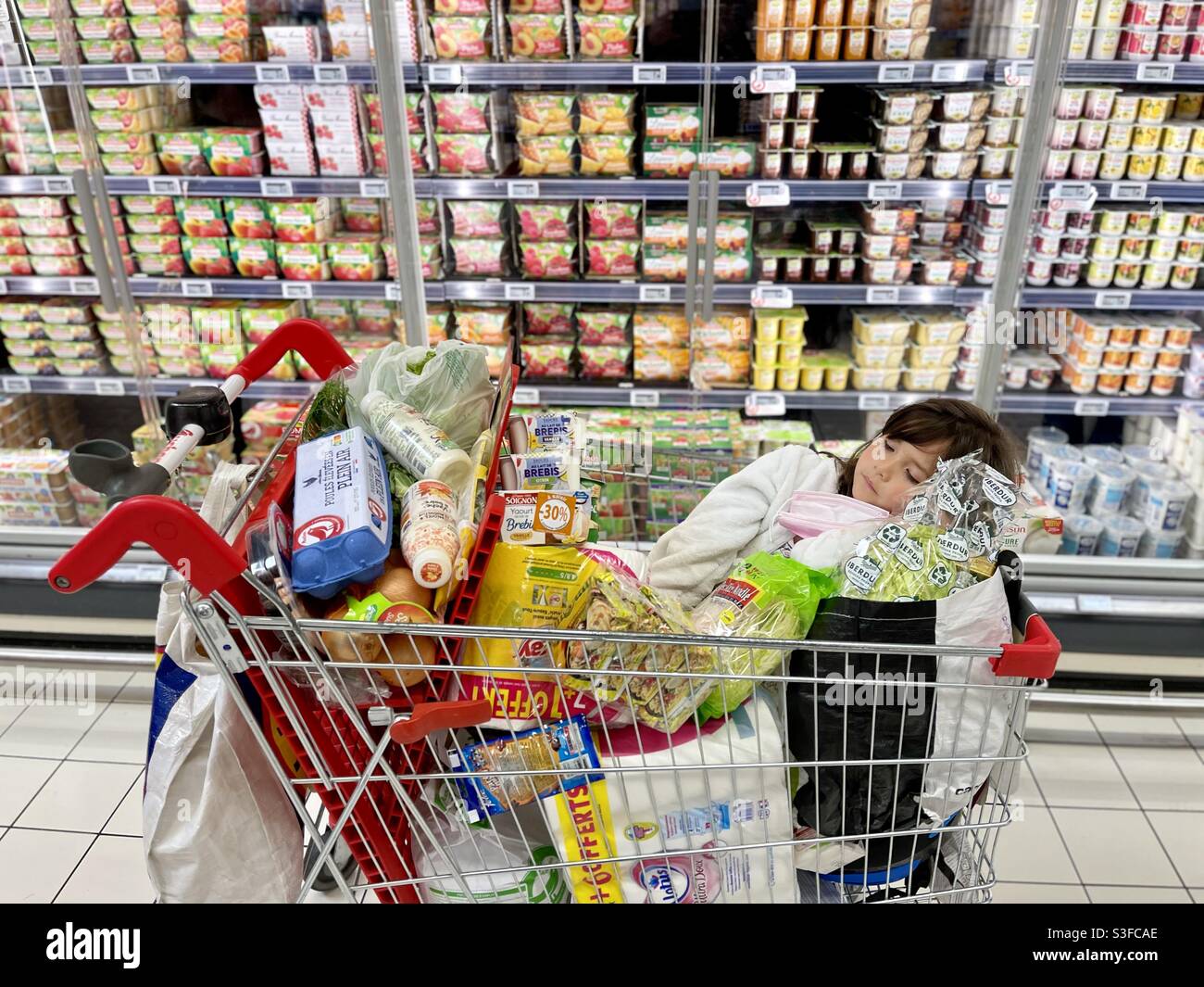 Mixed Asian Filipino little girl sleeping in a shopping cart, in a