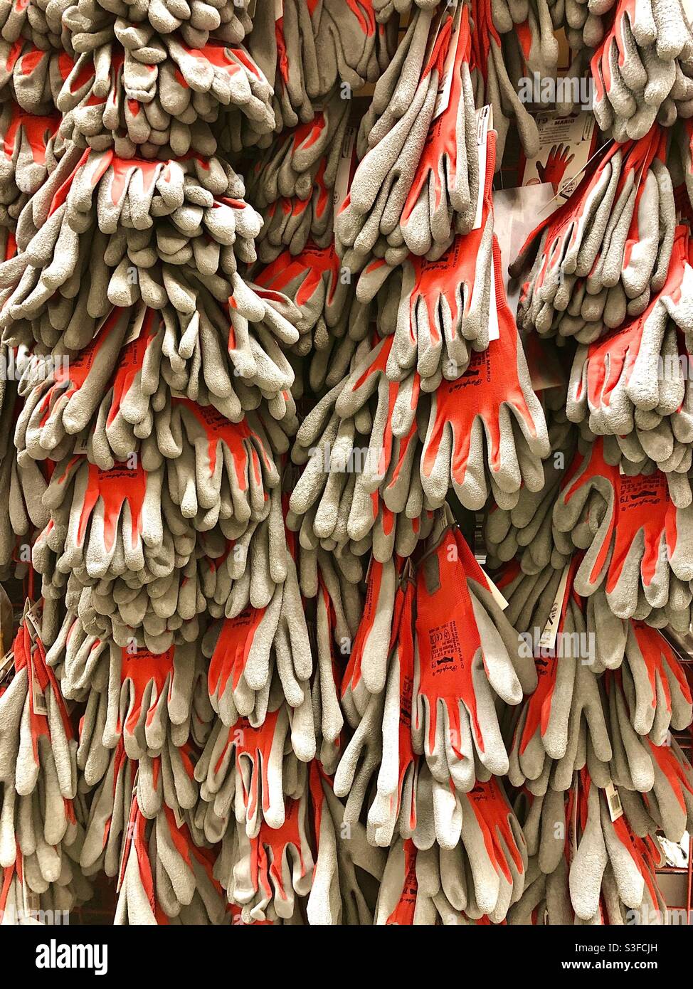 Rack of red and white rubber gloves for gardeners and builders. Stock Photo