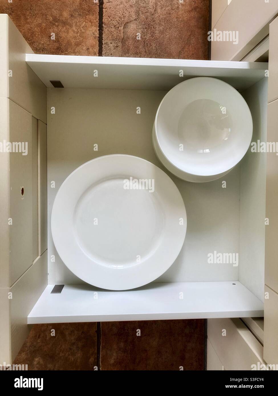 Plate drawer with white plates and bowls from above crockery Stock