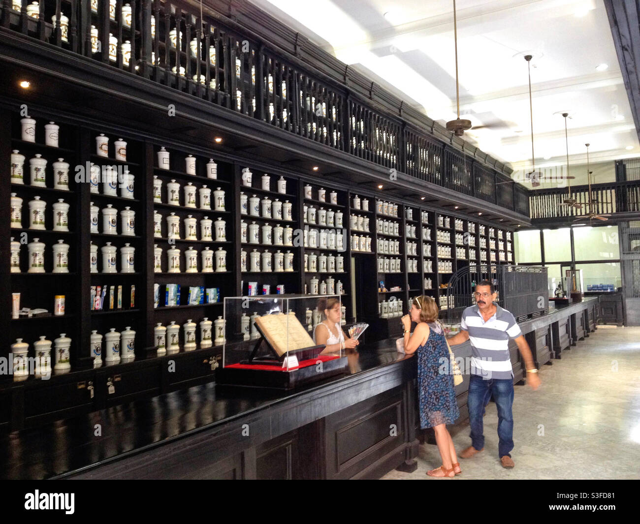 People inside an old fashioned pharmacy, chemist shop or drugstore with ceramic jars lining the wall, Havana, Cuba Stock Photo