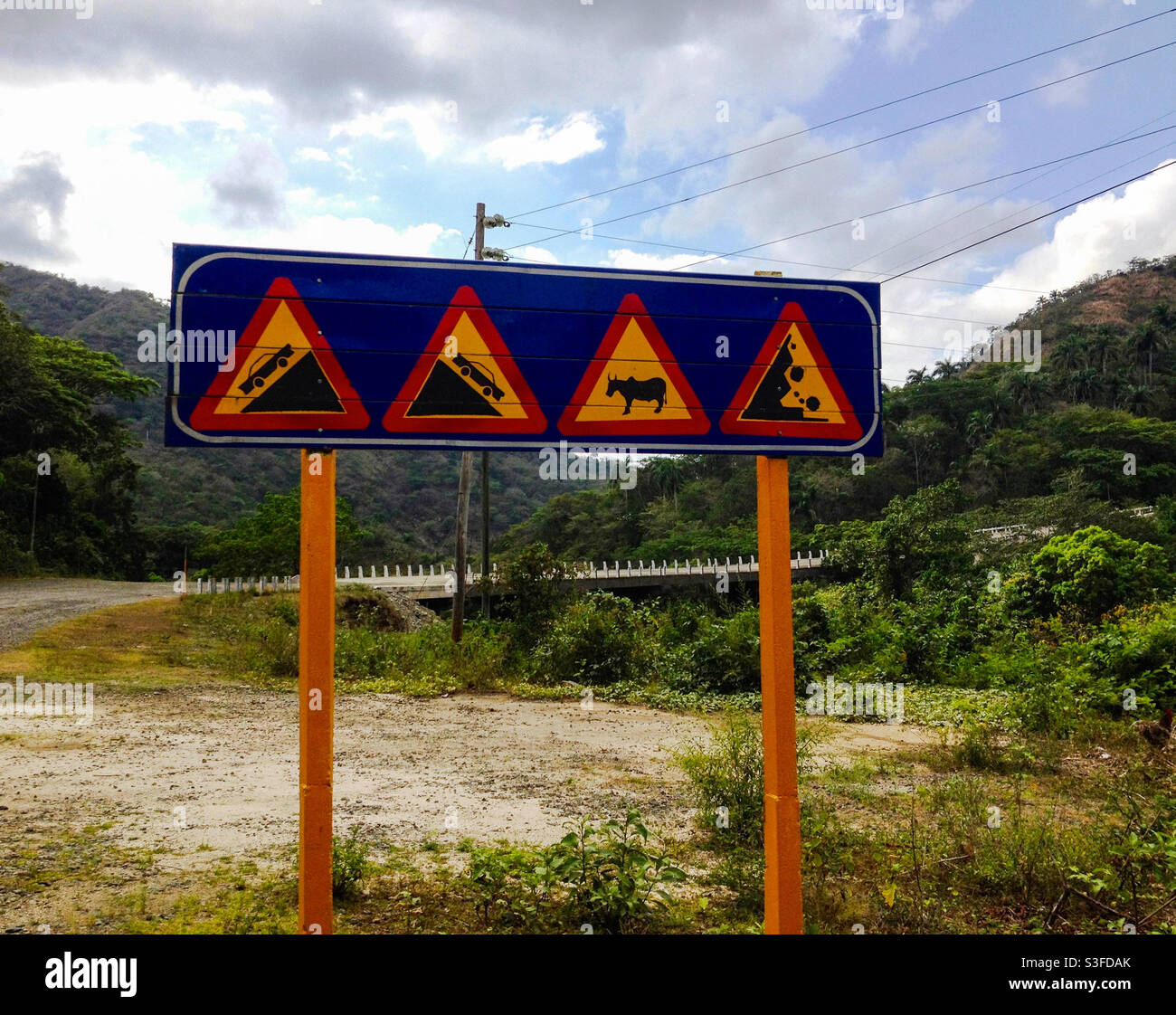Road signs warning of steep incline and descent, danger of animals in road and rockfall in foothills of Sierra Maestra, Cuba - Smartphone Captured Stock Image