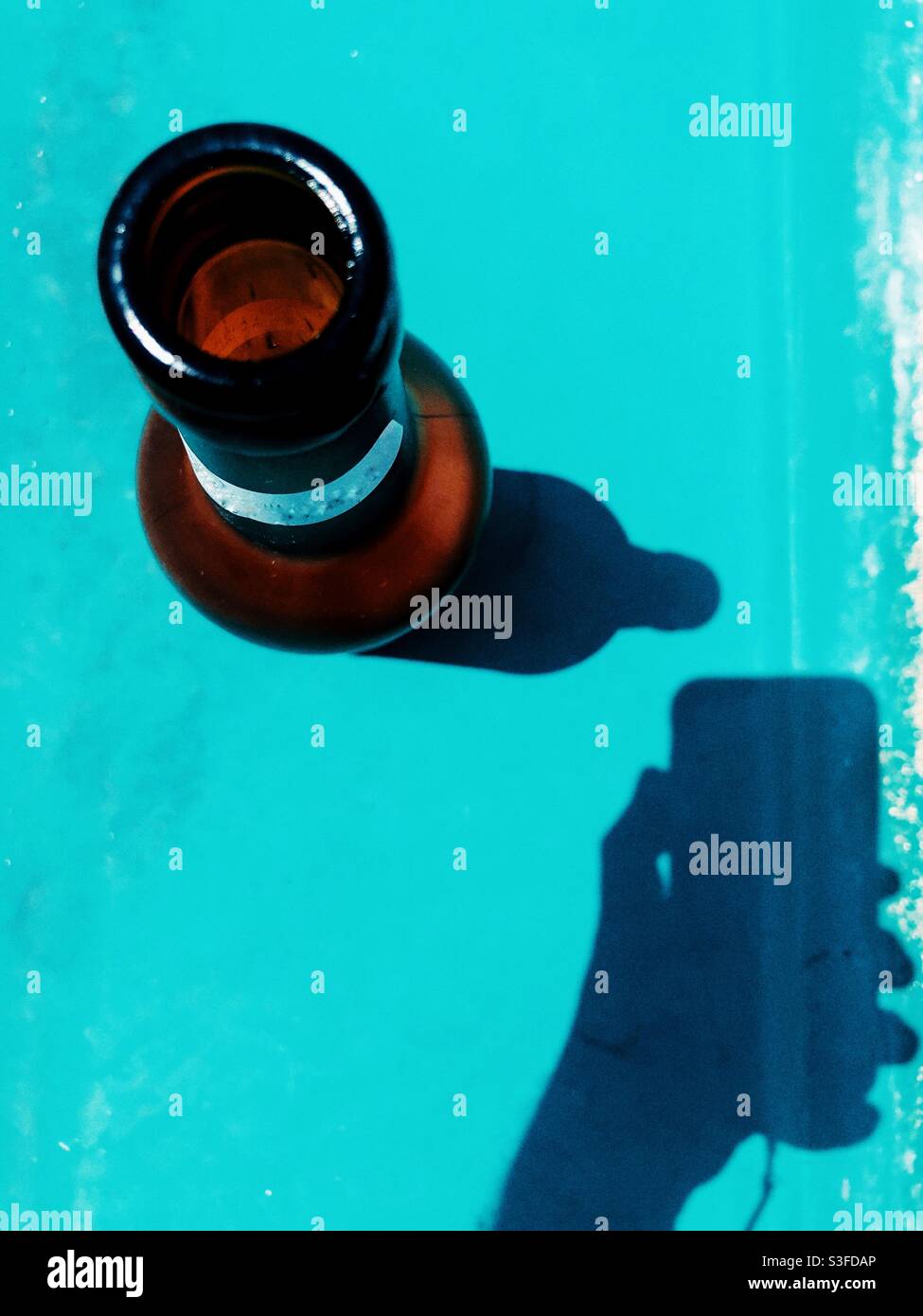 Beer bottle and shadow  of a person with a smart phone in hand - Smartphone Captured Stock Image