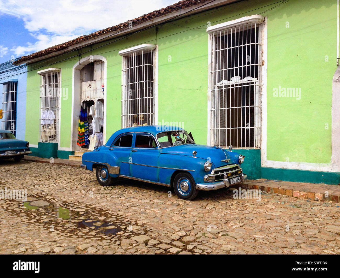 Old vintage American car parked outside a colourful old style house on cobbled street in Trinidad, Cuba - Smartphone Captured Stock Image