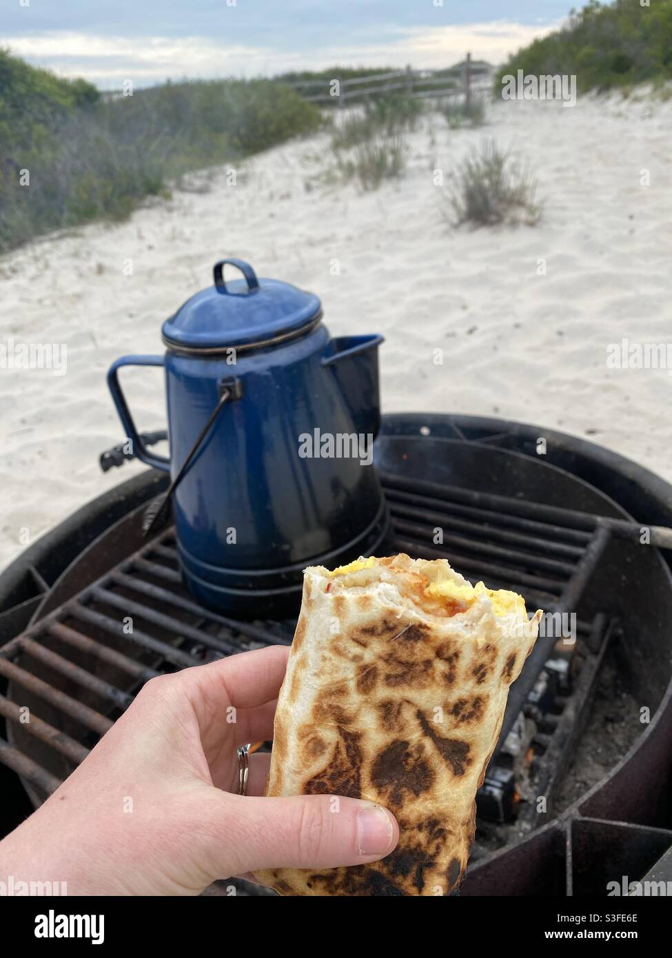 A freshly grilled breakfast burrito makes for a hot and delicious morning meal at the beach. - Smartphone Captured Stock Image