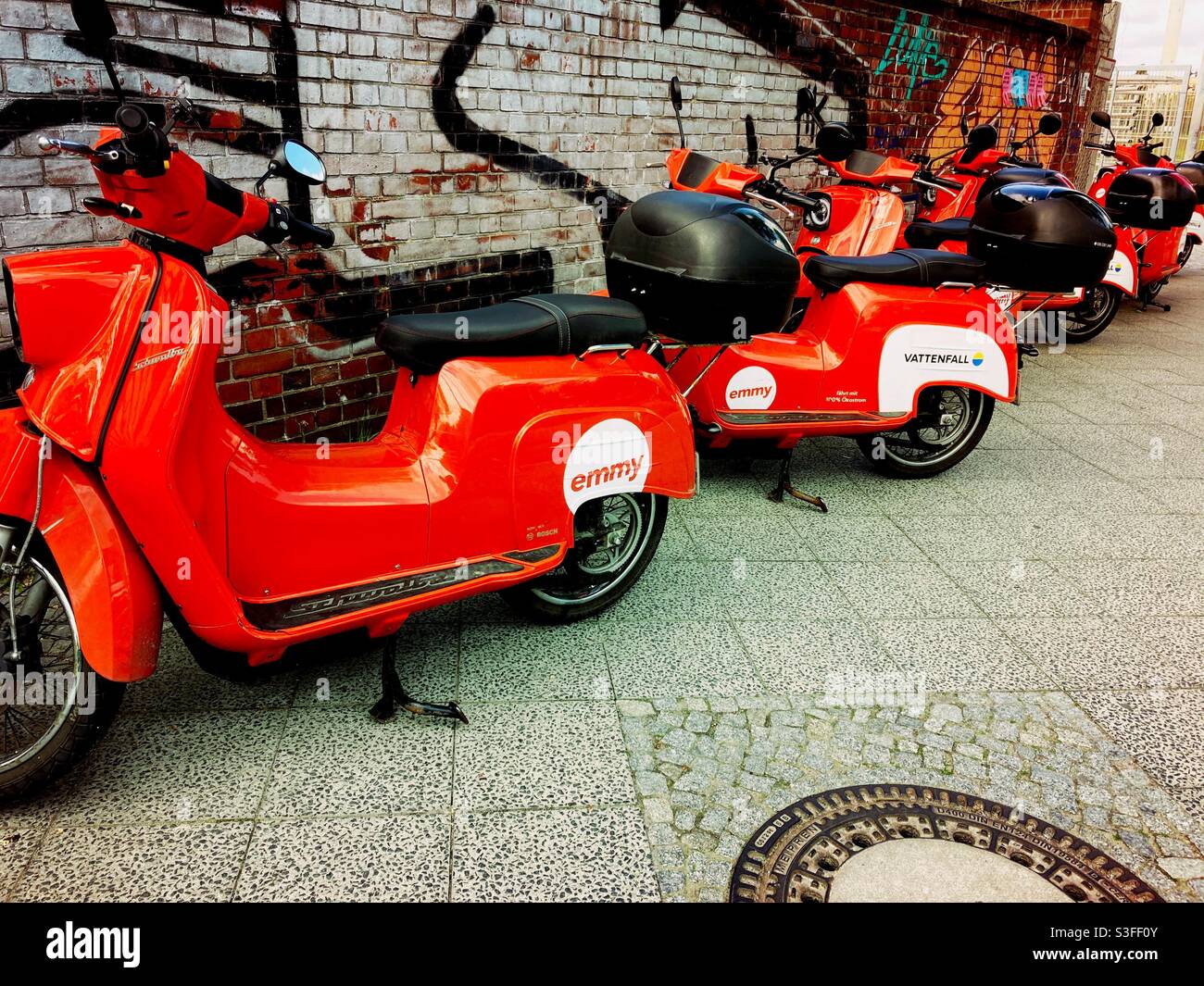 Emmy Scooters in Front of a Brick Wall on the Sidewalk on a Spring Day, Berlin, Germany, 2021 - Smartphone Captured Stock Image