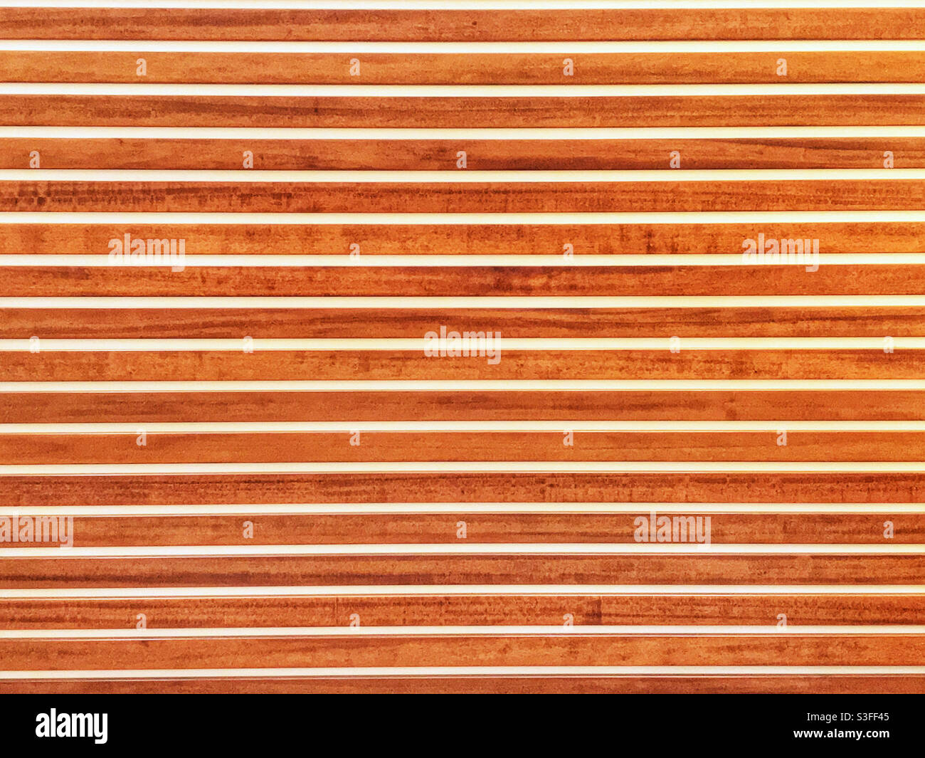 Stained wood horizontal panels spaced apart on a wall. Stock Photo