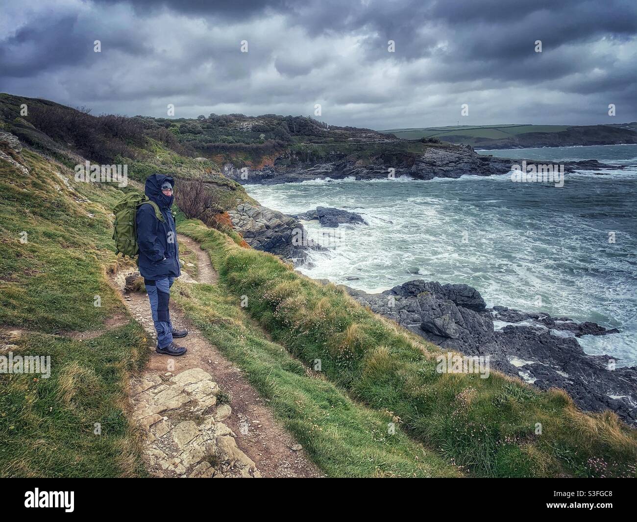 Man walking the South West Coast Path in Cornwall, on a stormy day. Stock Photo