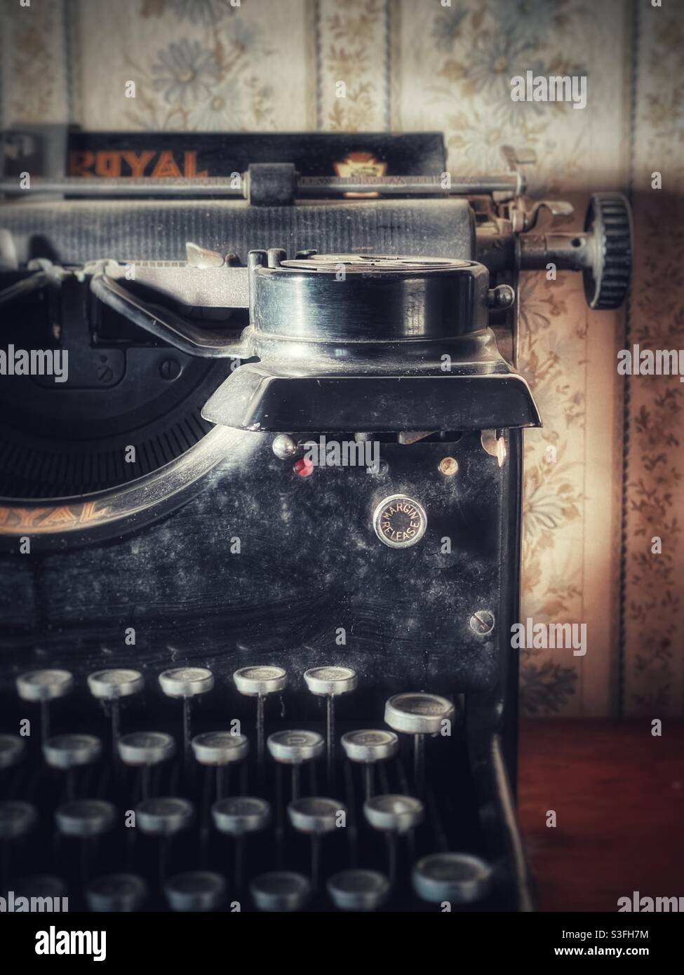Crusty old vintage typewriter against a vintage floral wallpaper - Smartphone Captured Stock Image
