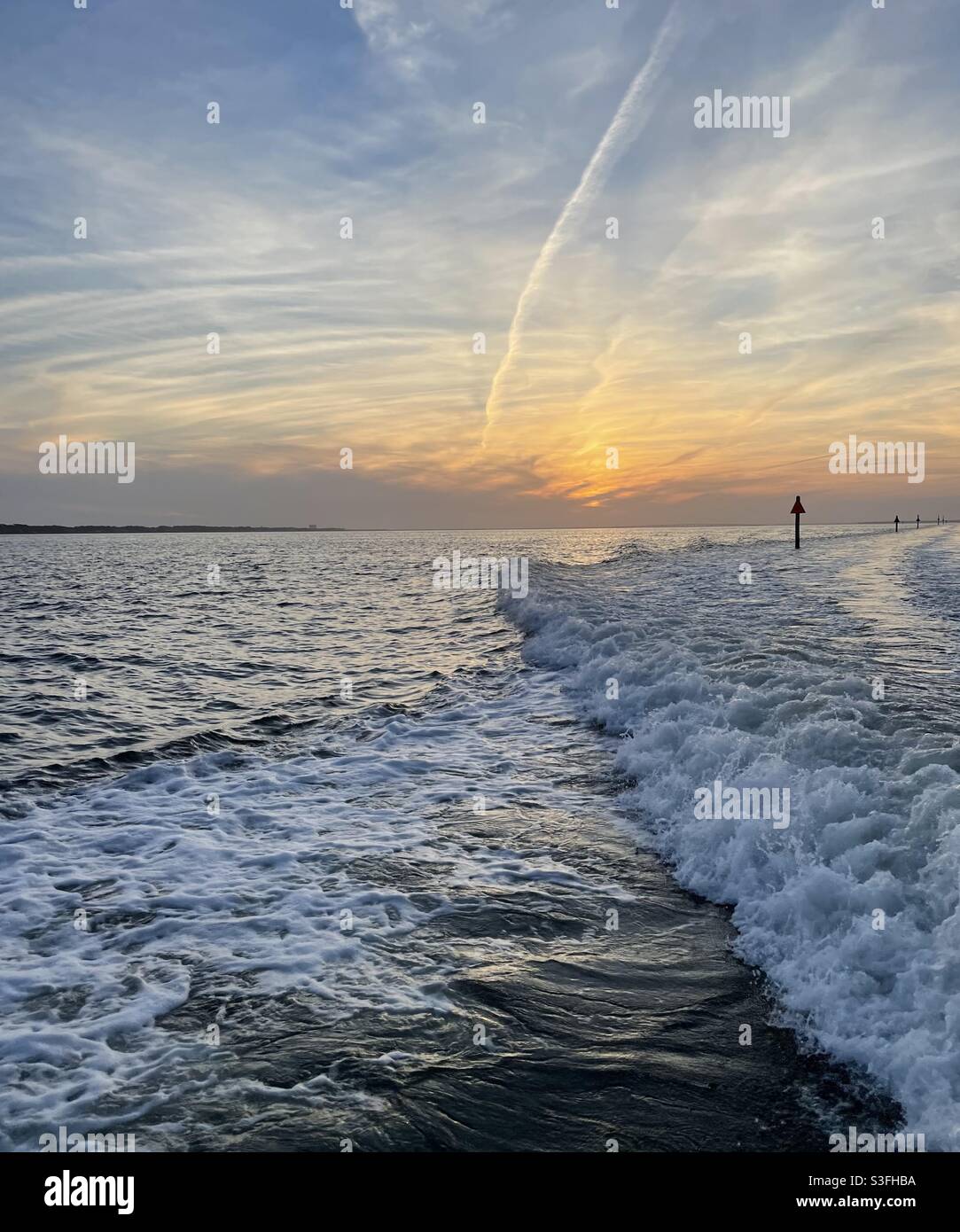 Colorful sunset skies with boat wake and plane contrails in the sky over the Gulf of Mexico Florida - Smartphone Captured Stock Image
