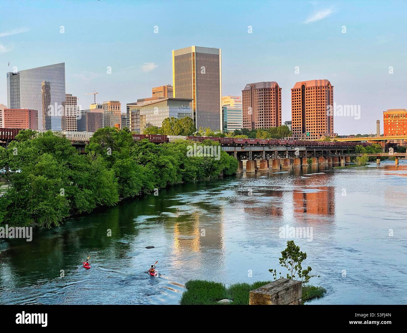 Two kayakers floating down the James River through downtown Richmond, Virginia as a train rolls by. Stock Photo
