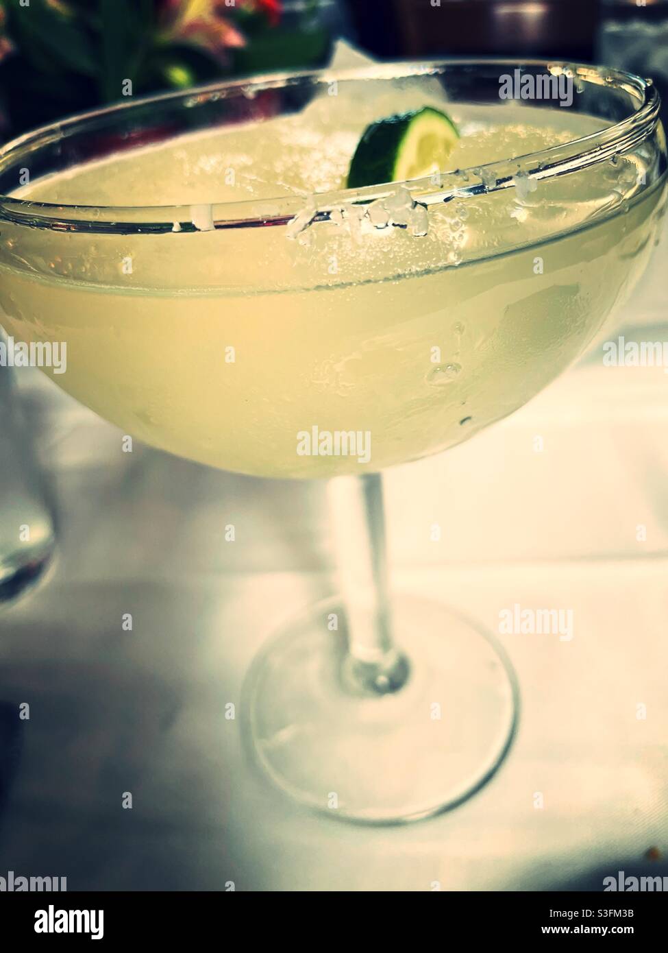 Close up of a frozen margarita cocktail in a salted rimmed glass at