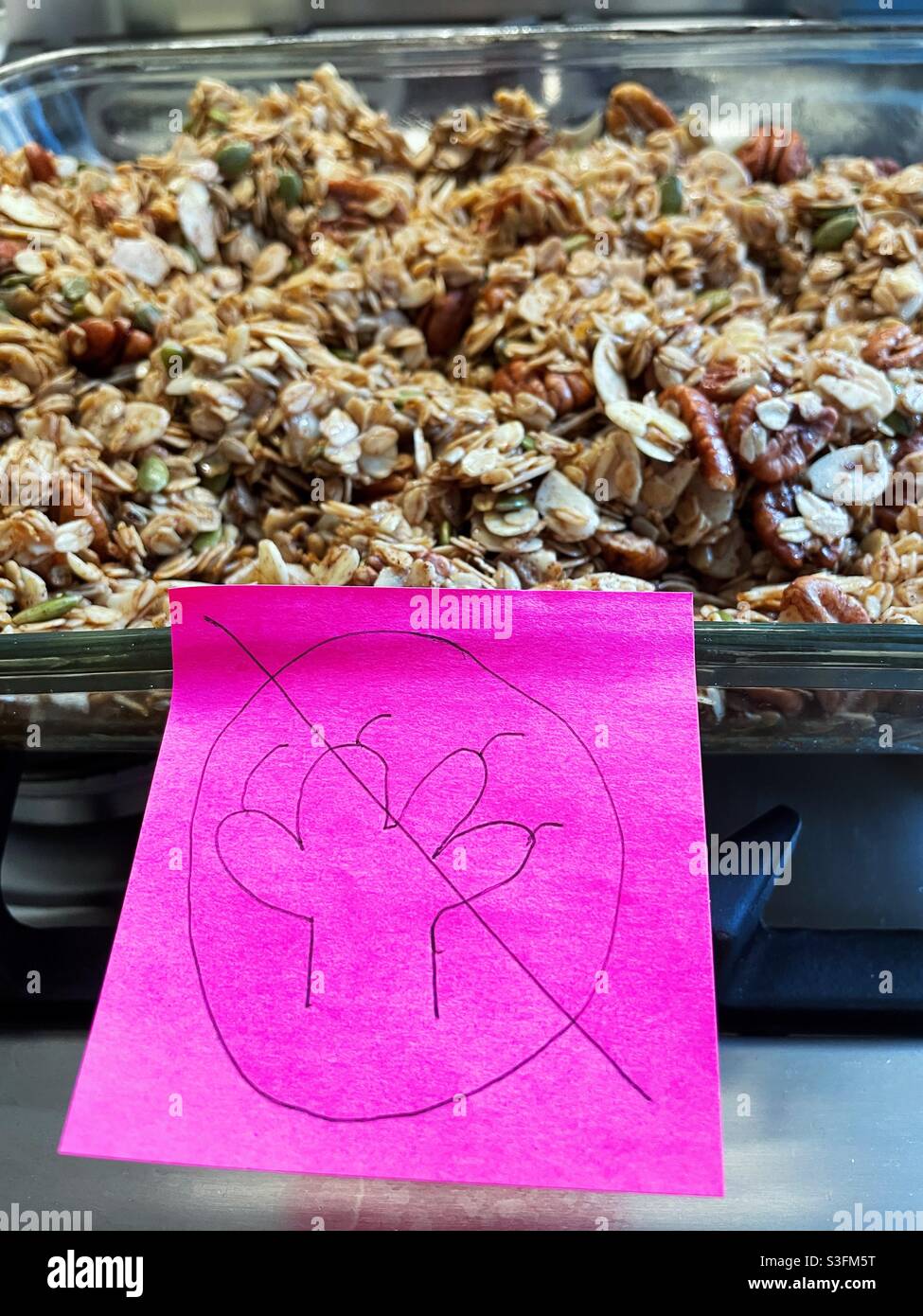 Don’t touch humorous hot pink posted sticker on a freshly baked pan of granola in a residential kitchen, USA - Smartphone Captured Stock Image
