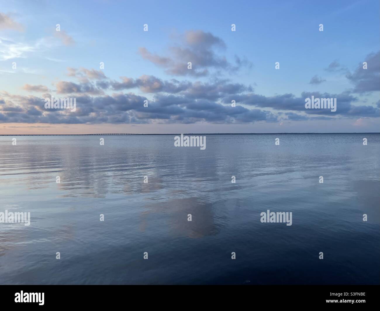 Soft sunset skies reflecting onto calm bay water Stock Photo - Alamy