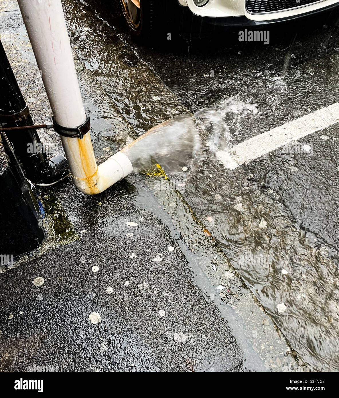 Rainwater spills from a drainpipe into the gutter in Cuba Street Wellington New Zealand during a storm Stock Photo