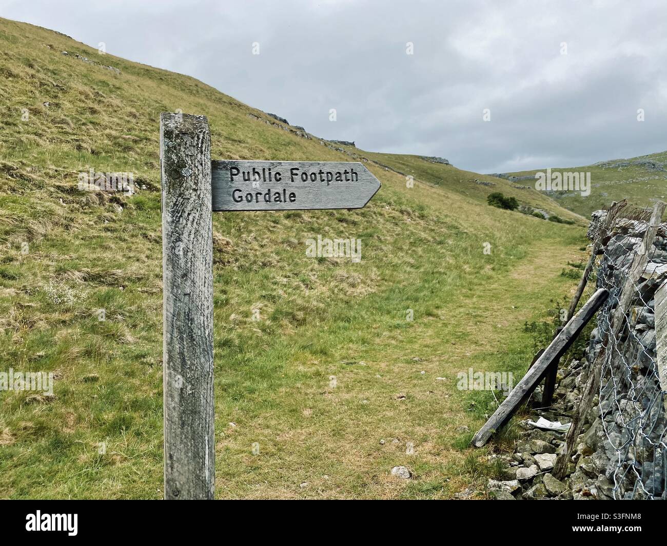 Scenic rural landscape with dramatic grey sky in Malham, Yorkshire Dales National Park, UK. Rolling hills and green pastures with dry stone walls. Hill walking - Smartphone Captured Stock Image