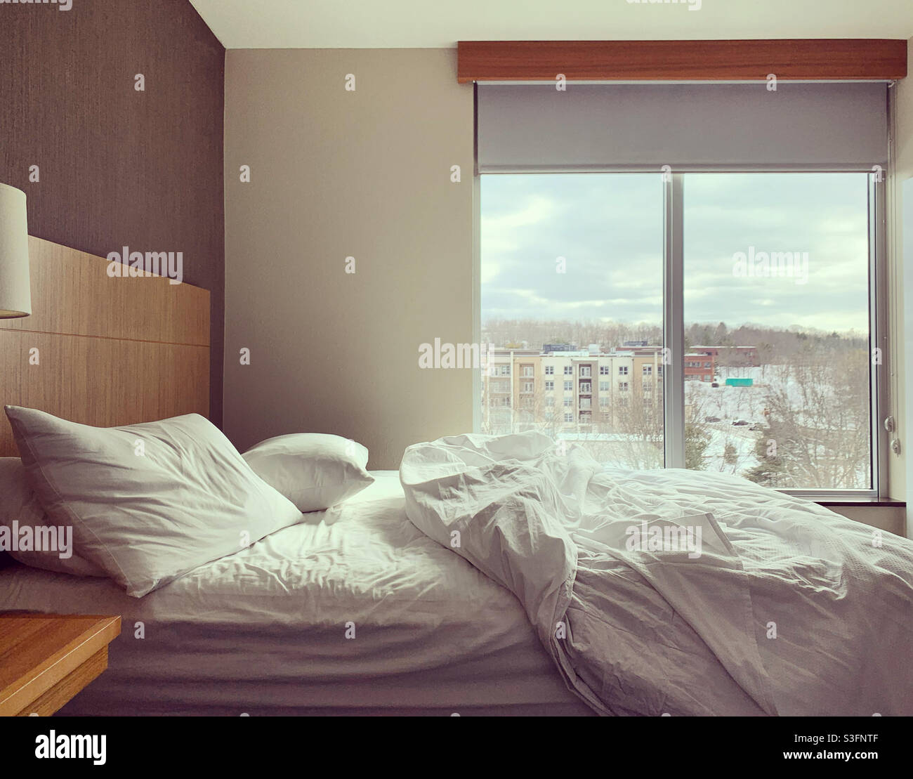 A bed with tousled bedding in a room with minimalist design Stock Photo