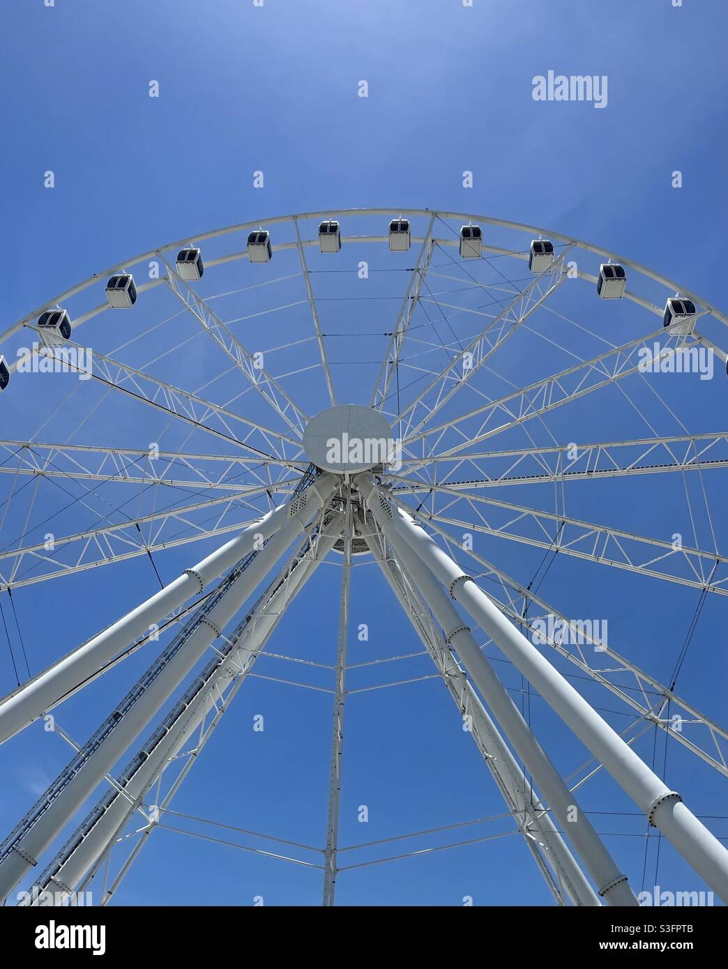Looking up at a large outdoor sky wheel with clear blue sky background ...