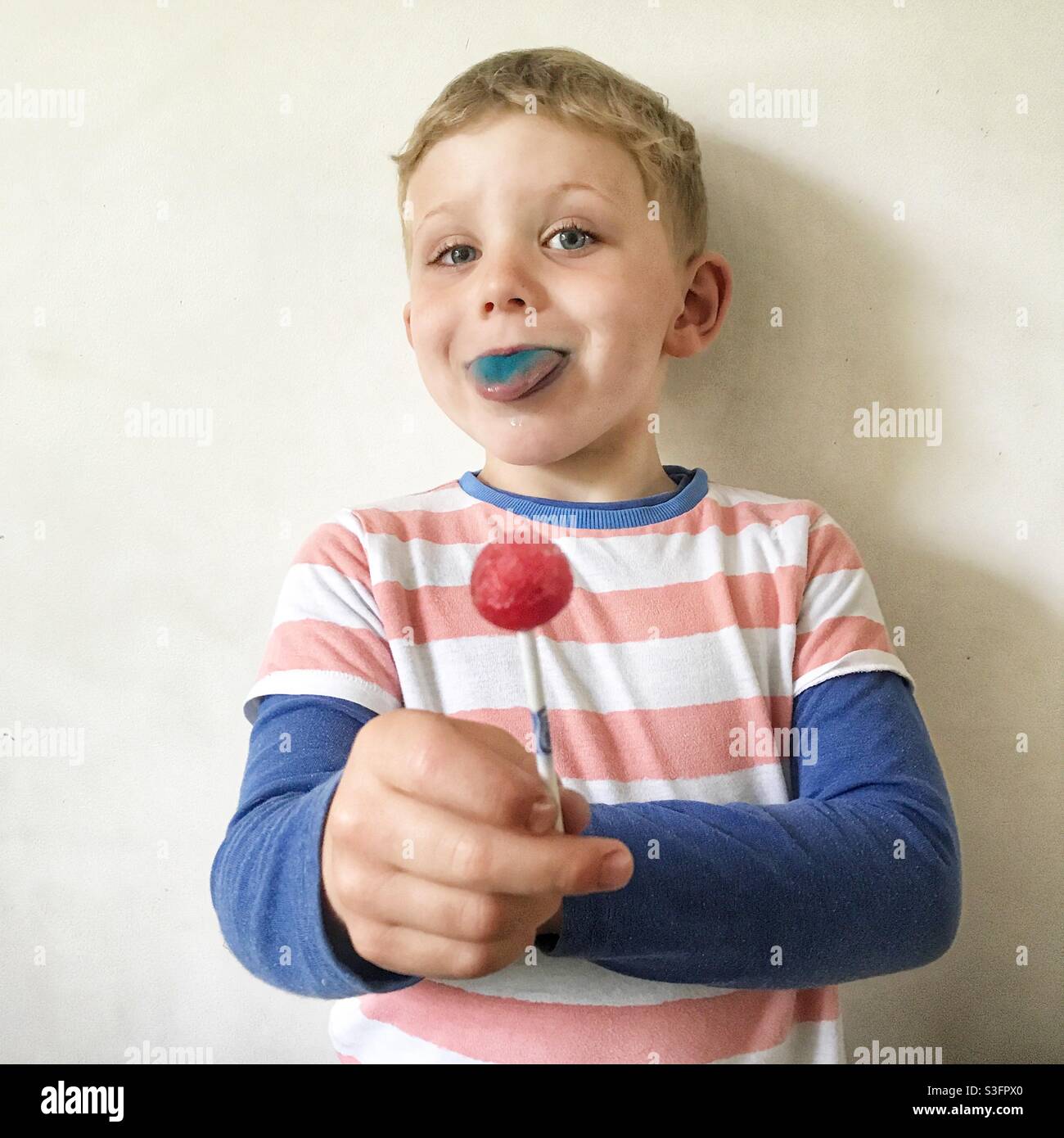 Four year old boy with a red lollipop Stock Photo