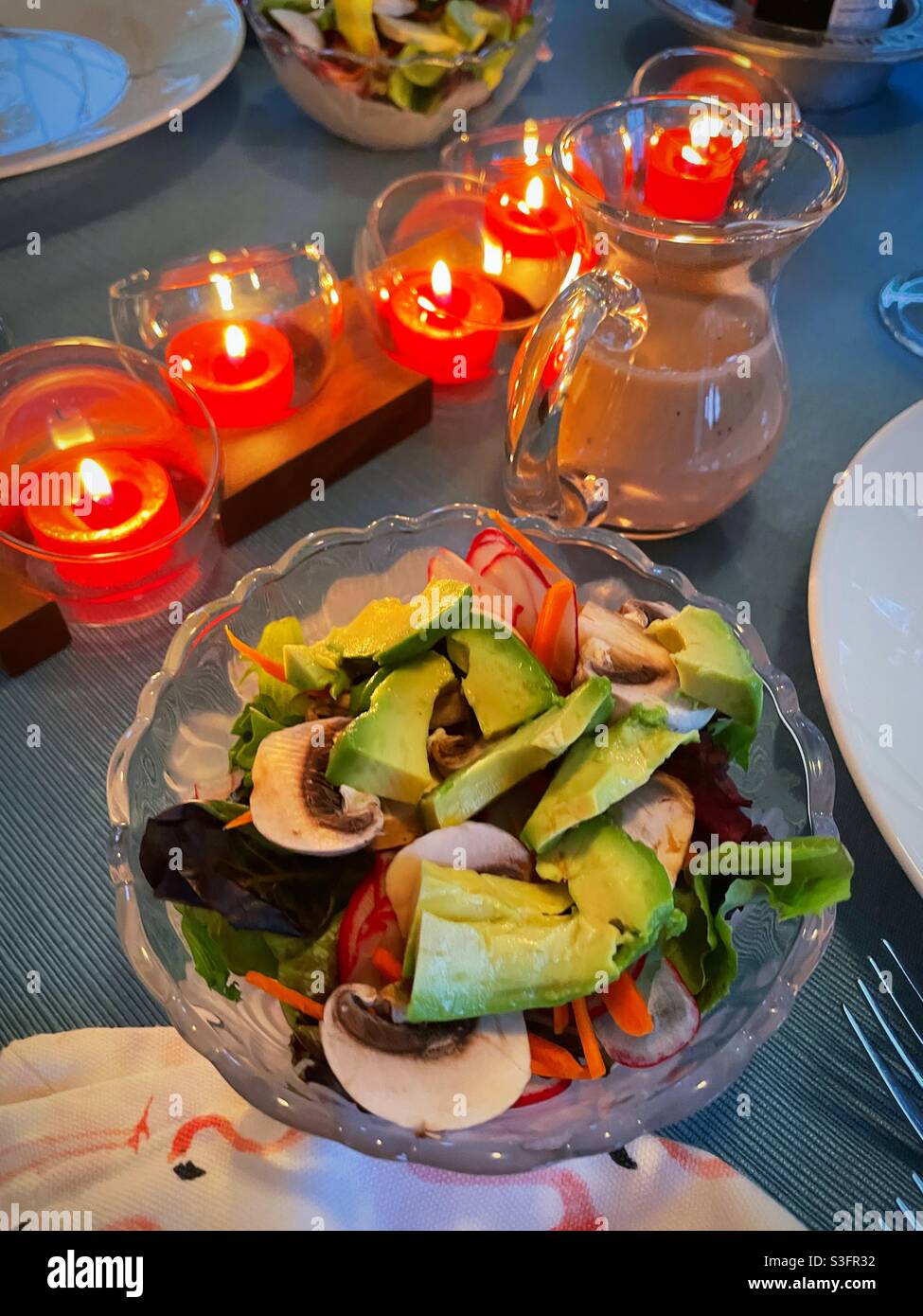 A festive votive candle centerpiece lights in healthy fresh salad with avocado and mushrooms, USA - Smartphone Captured Stock Image