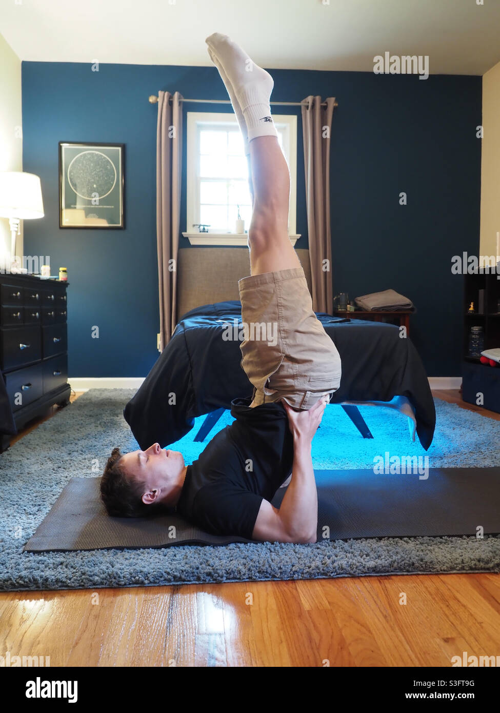 Yoga and fitness regimen at home, young man holding pose Stock Photo