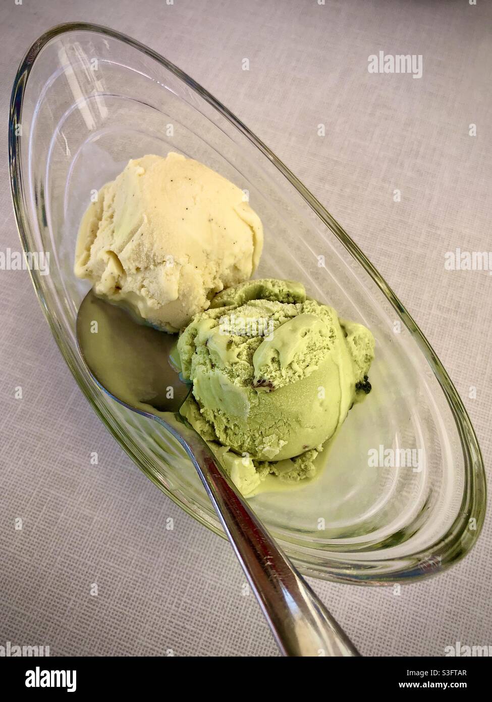 Glass dish with scoops of vanilla and pistachio ice cream. Stock Photo