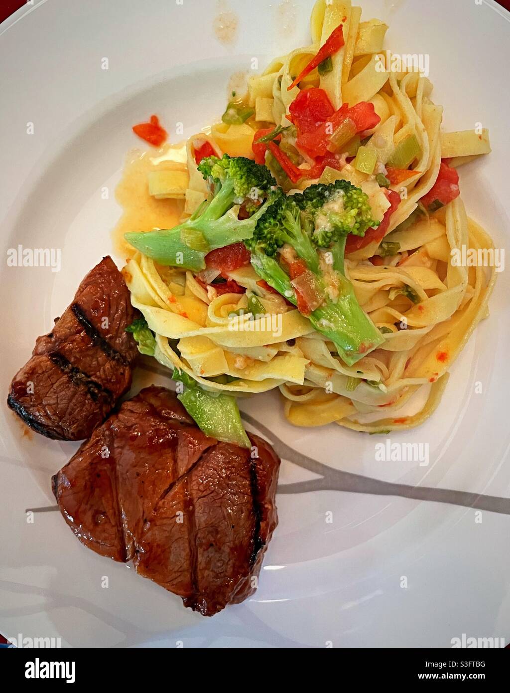 Flat lay close up of a gourmet meal of grilled pork tenderloin and fettuccine Primavera - Smartphone Captured Stock Image