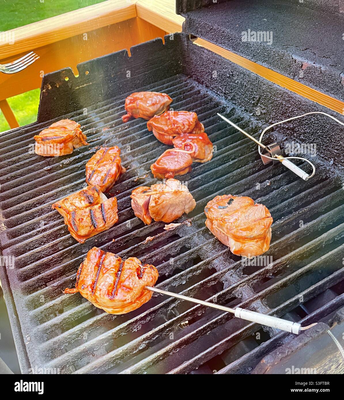 Pork medallions cooking on a backyard residential grill with electronic