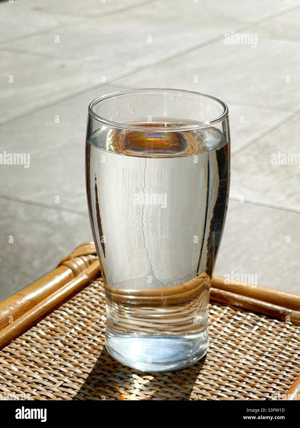 Pint glass of water on a garden table. Stock Photo