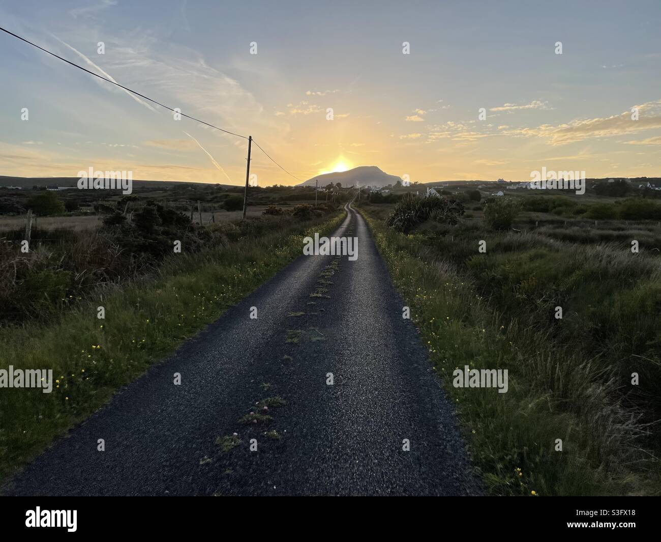 An empty road leading up to a sunset on Achill Island, County Mayo, Ireland. Stock Photo