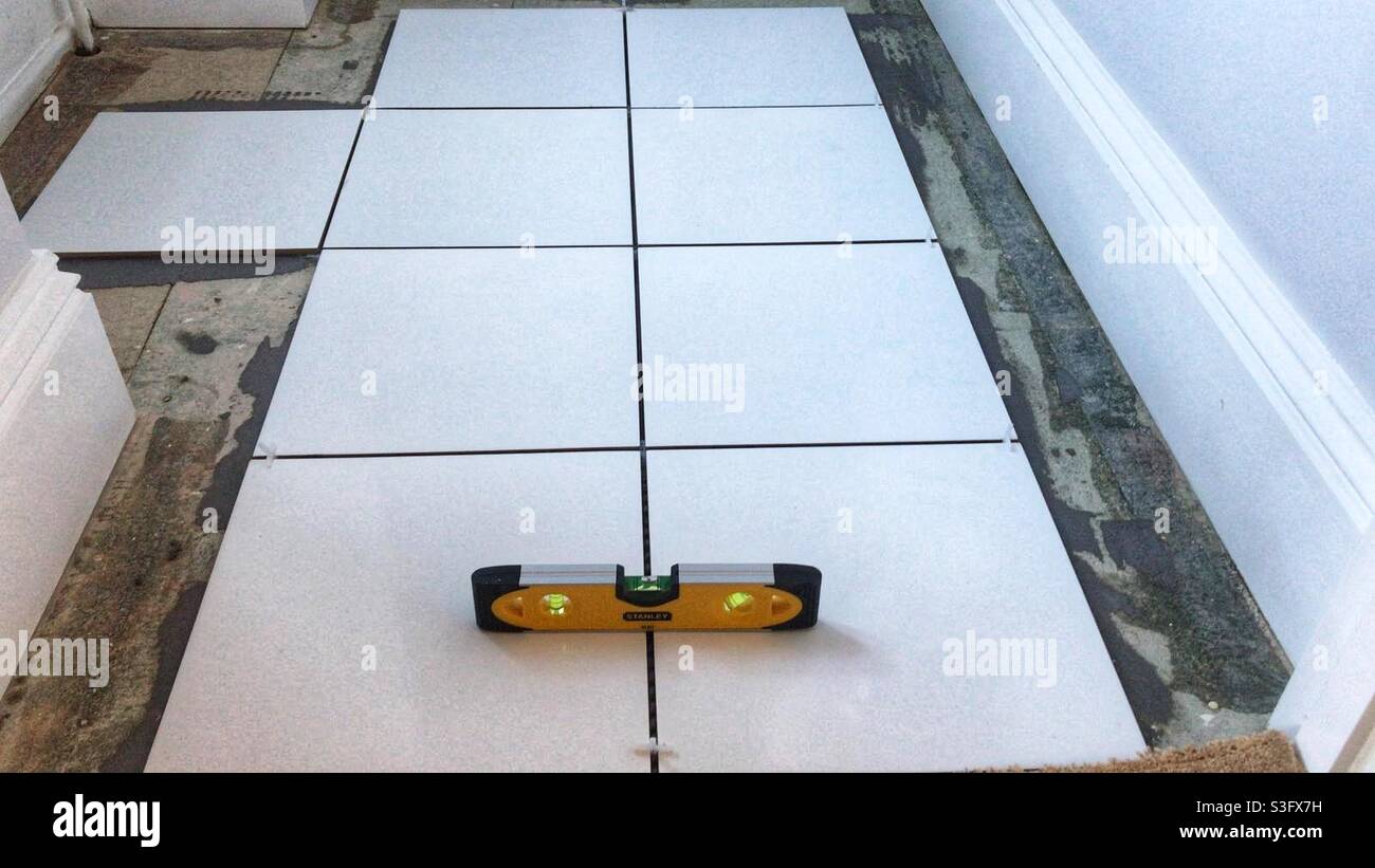 Floor tiles tiling a bathroom floor with a spirit level on top Stock
