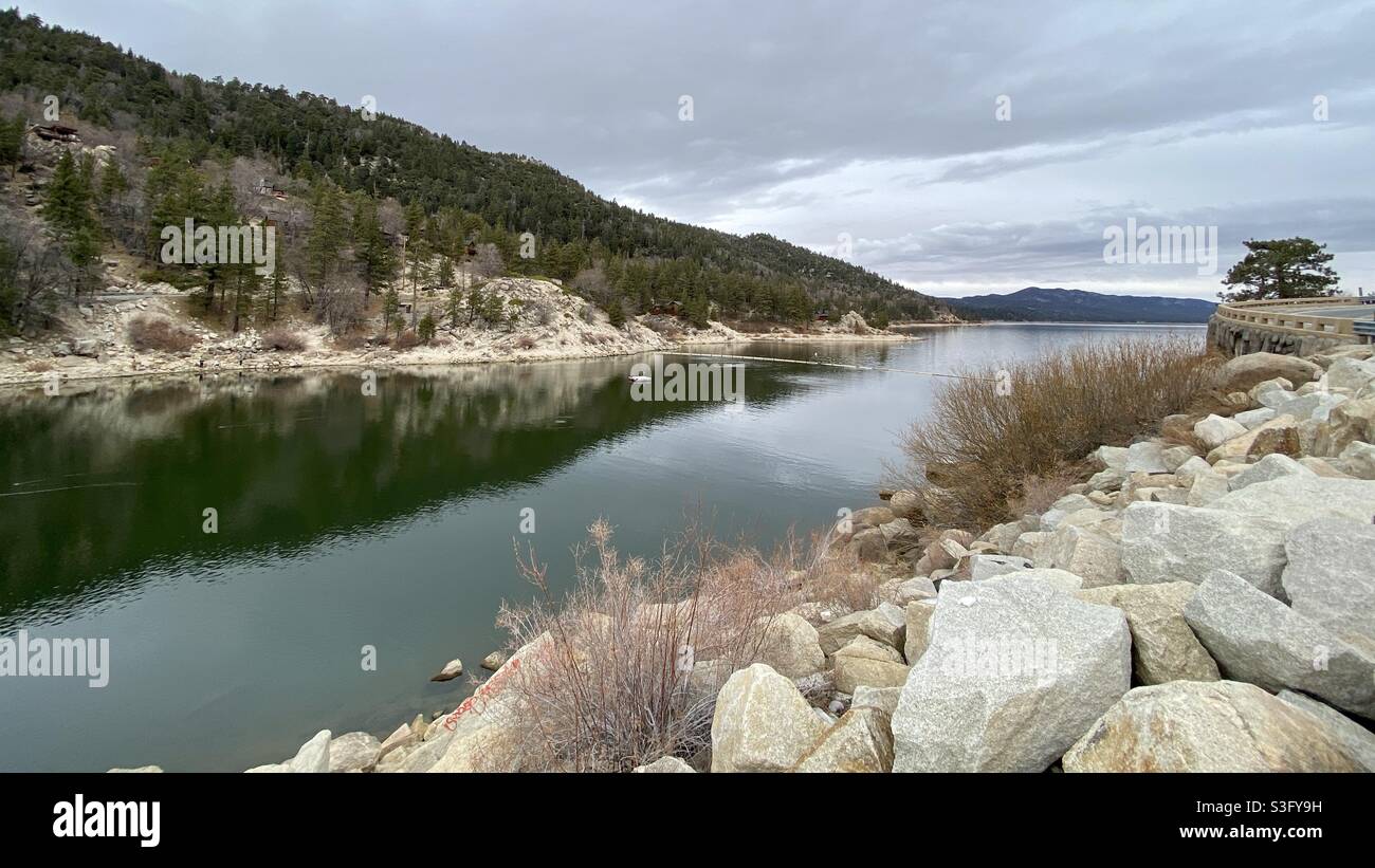 Big Bear Lake, California, on Christmas Eve, 2020, with overcast skies and large rocks leading up to Big Bear Dam in the foreground. Stock Photo