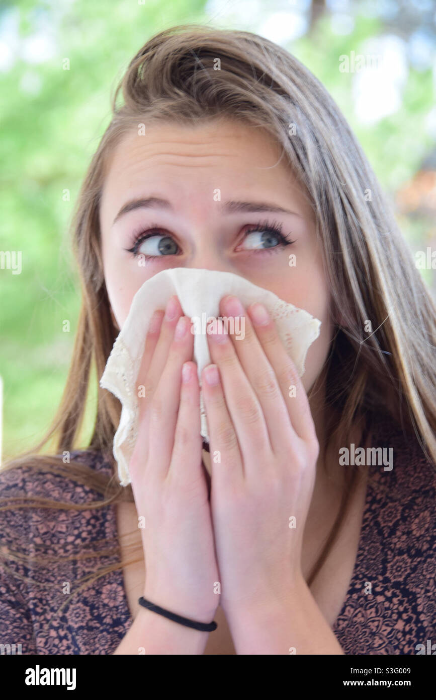Allergy season, young woman outdoors with handkerchief covering her face - Smartphone Captured Stock Image
