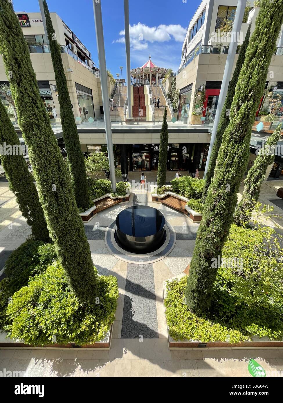 Park with fountain surrounded by cypress trees in an open sky mall in Béziers, Occitanie, south of France - Smartphone Captured Stock Image