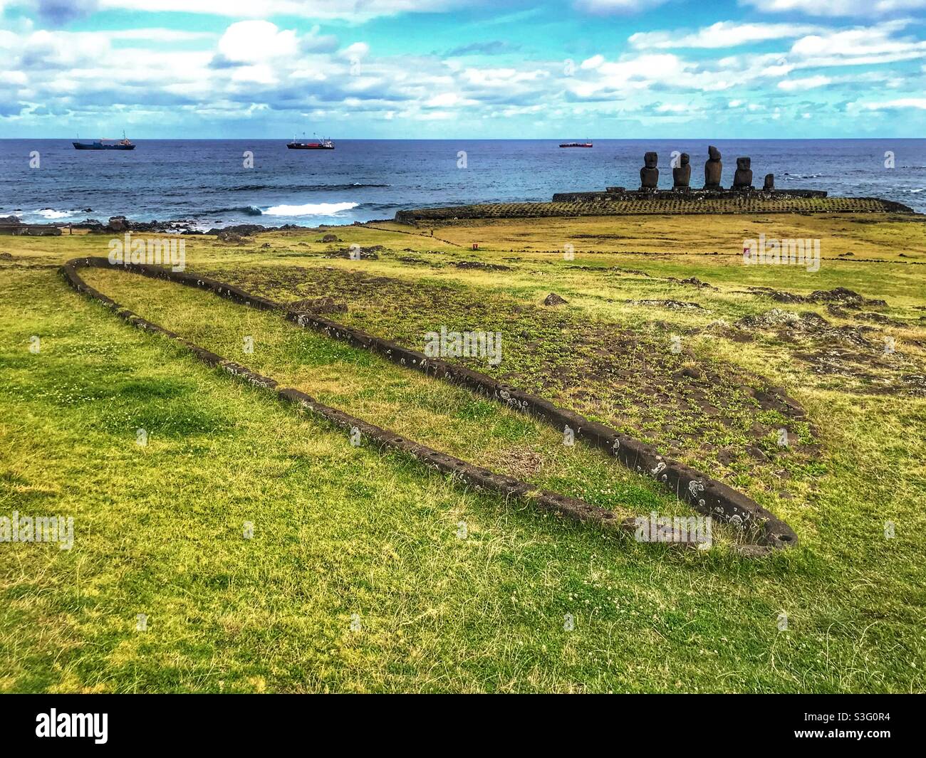 Historic house site with Moai statues in the background, Tahai complex, Easter Island, Chile - Smartphone Captured Stock Image