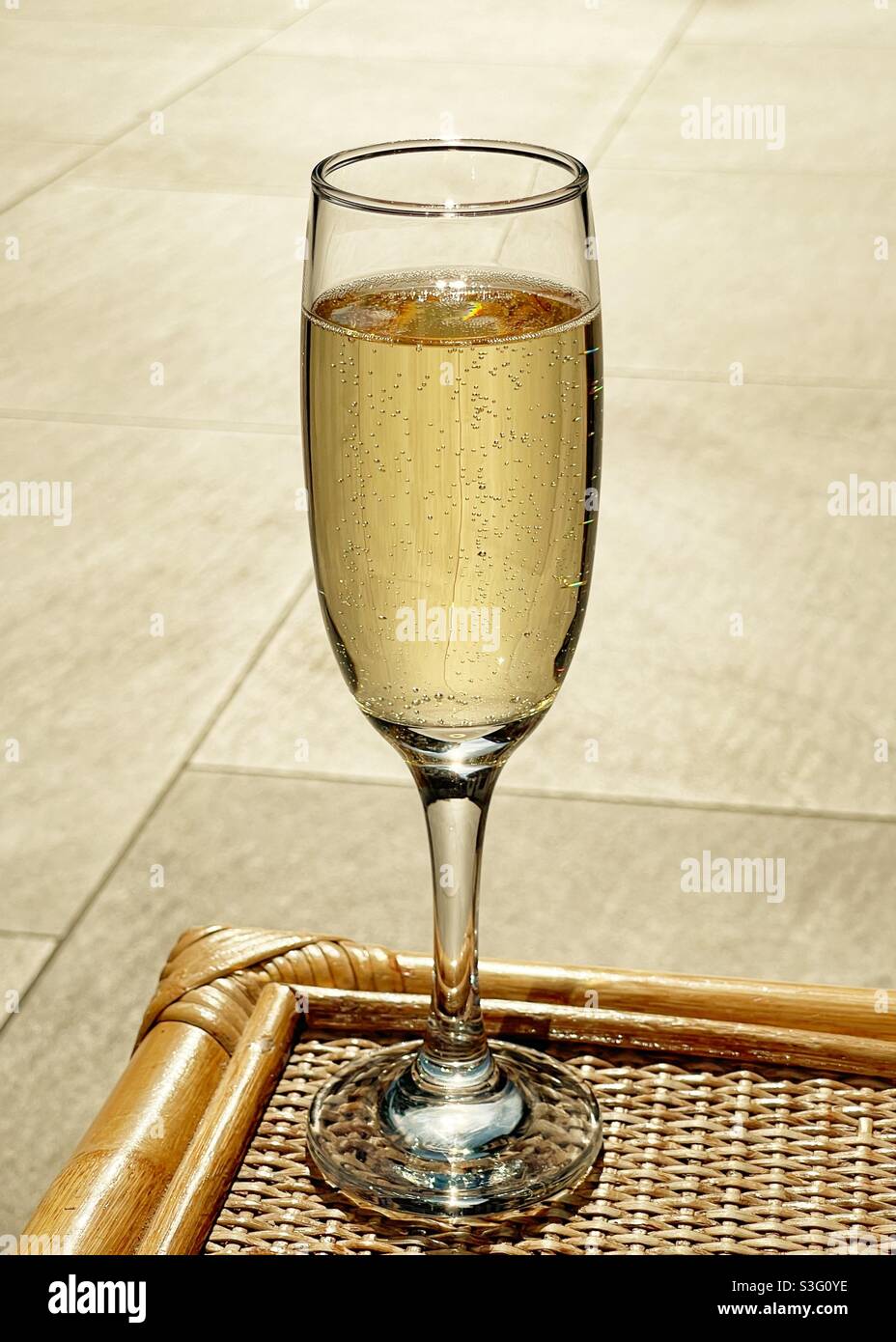 Flute glass of champagne on a garden table on a summer evening Stock Photo