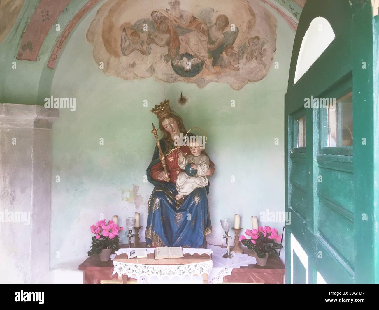 Old altar in an old catholic chapel in Bavaria with a wooden statue of the holy Mary and her boy child Jesus Christ - Smartphone Captured Stock Image