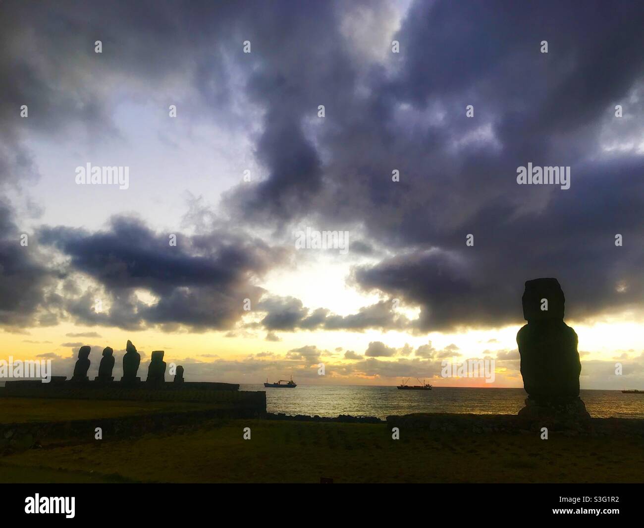 Moai at sunset with cargo ships in the background, Tahai complex, Easter Island, Chile - Smartphone Captured Stock Image