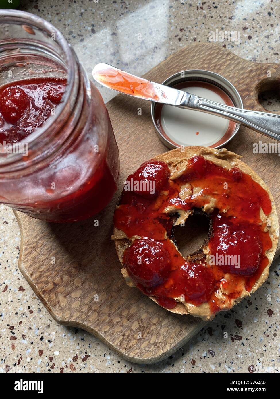 Homemade strawberry jam with natural peanut butter on a toasted bagel. Stock Photo